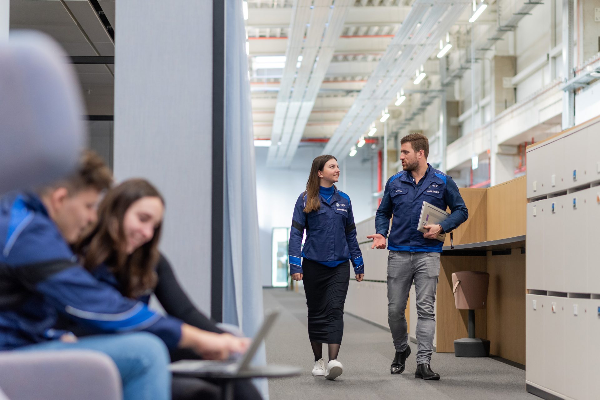 A man and a woman are working together on a computer while another man is walking by with another woman