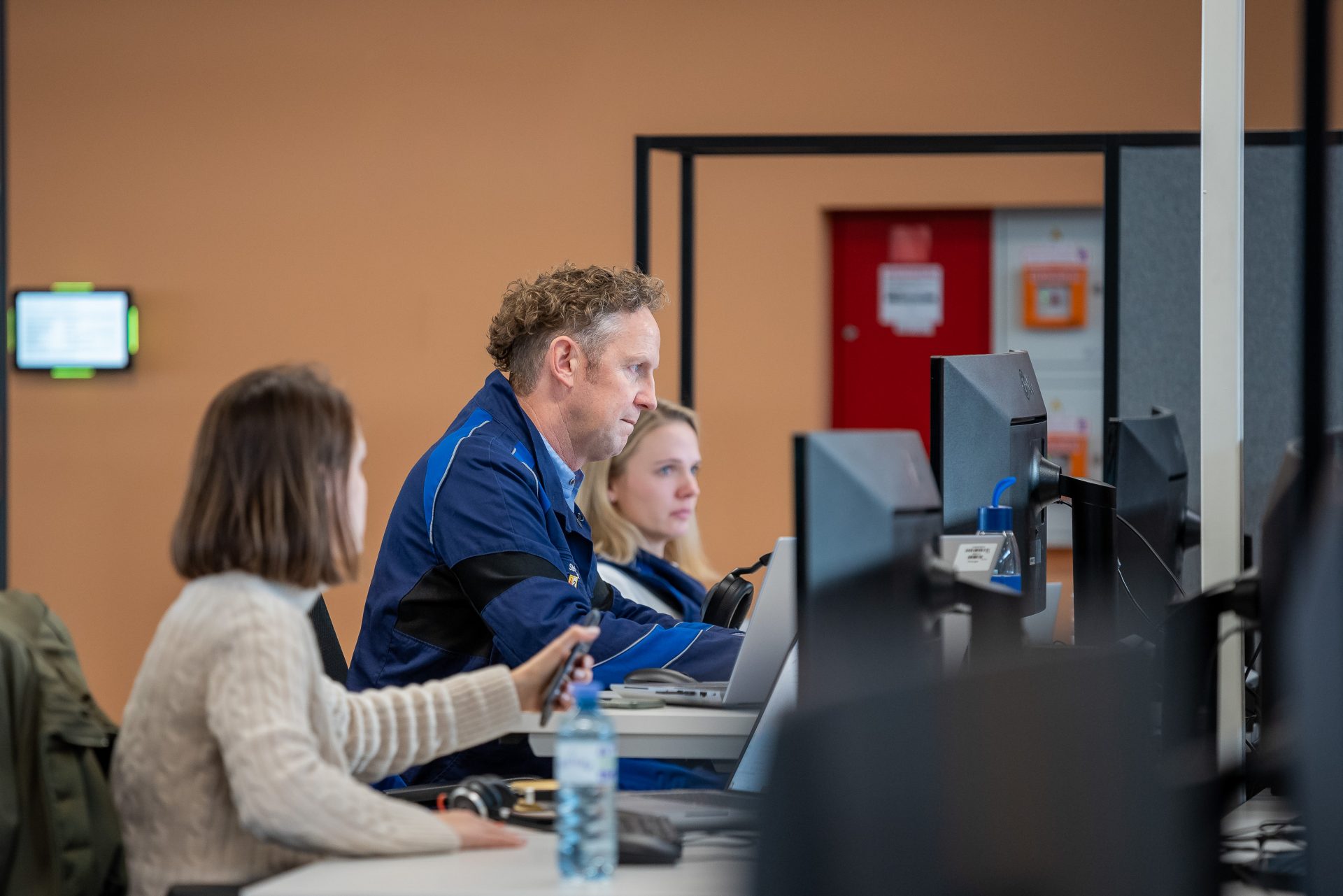 Three people are working on a computer