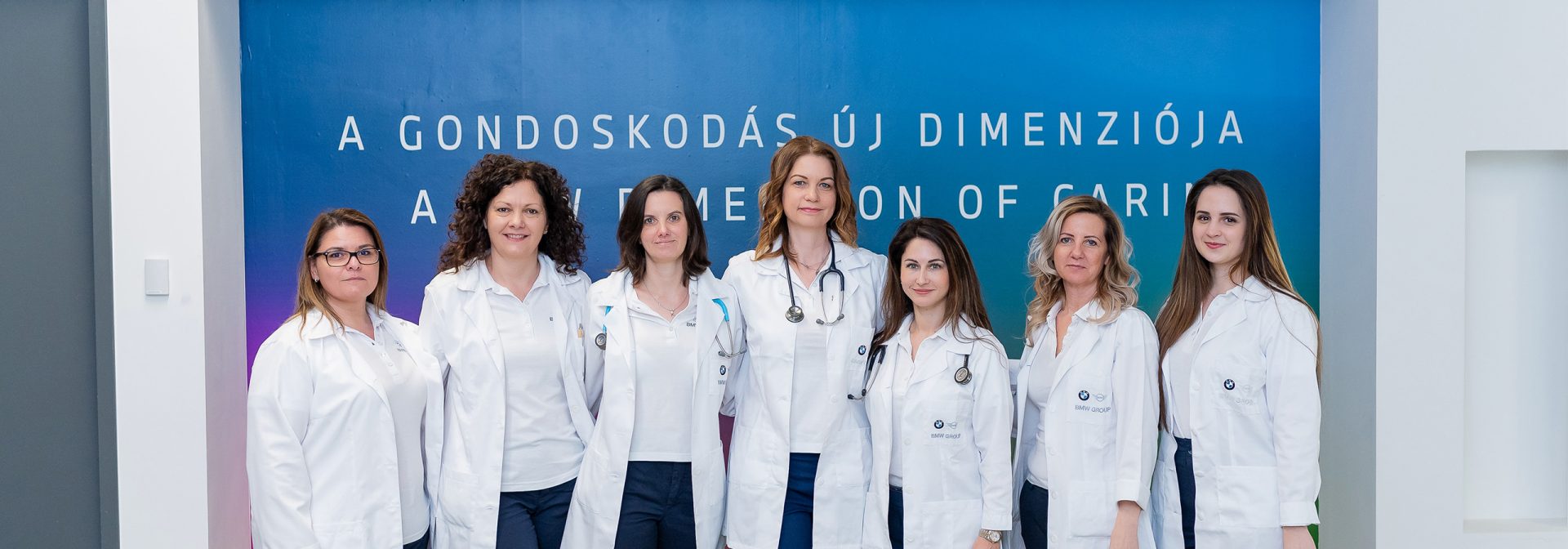 The employees are standing in front of a blue wall