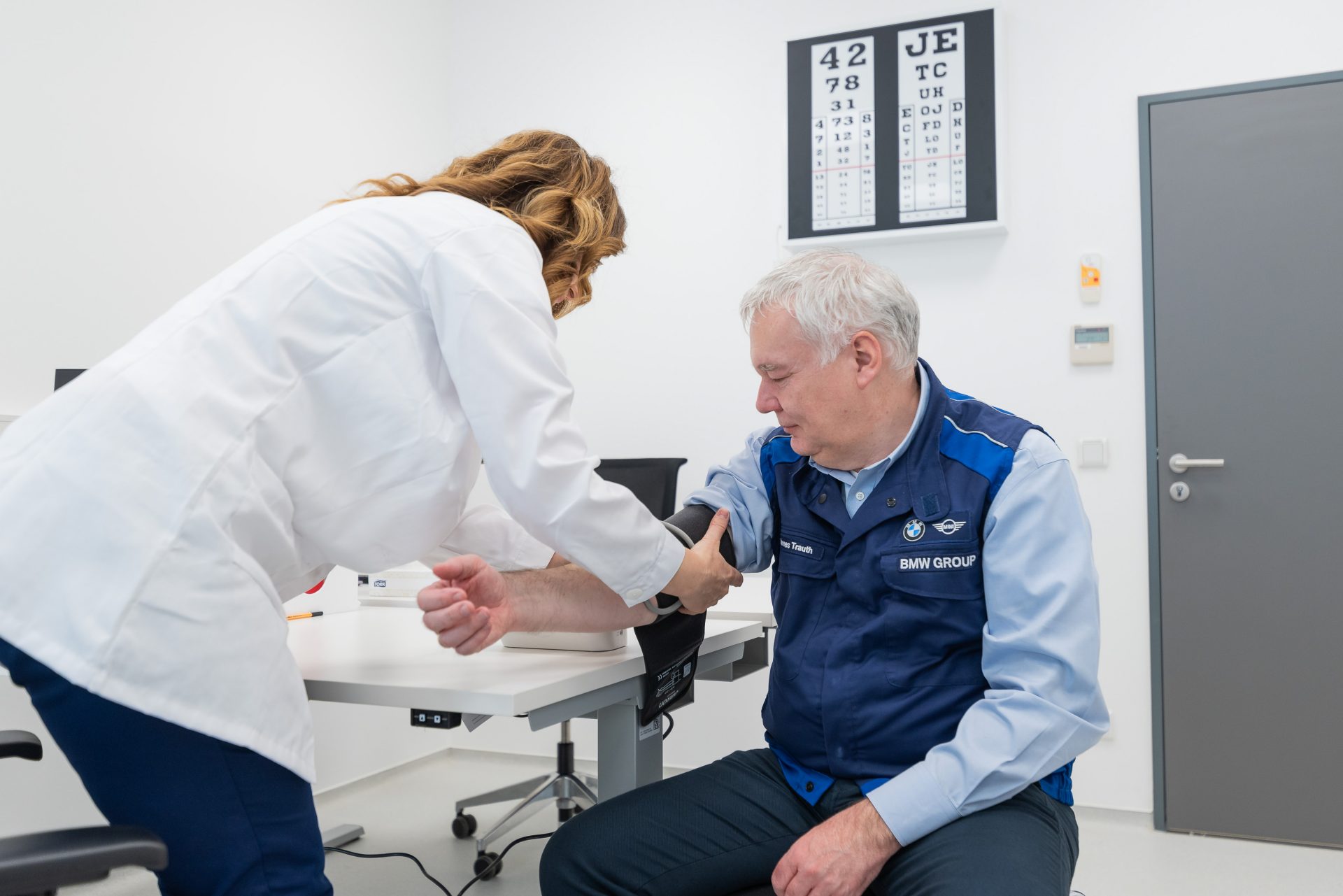 An employee is measuring the blood pressure on a mans arm