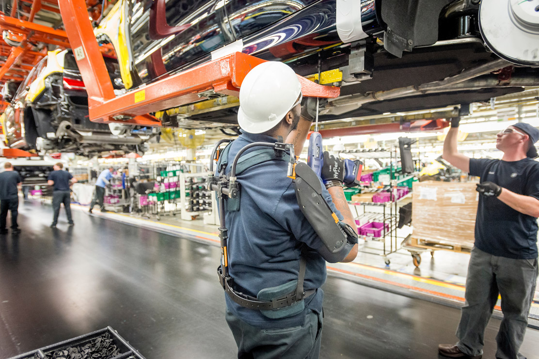 Associate in Assembly wears Exoskeleton Vest while working under a car body. 