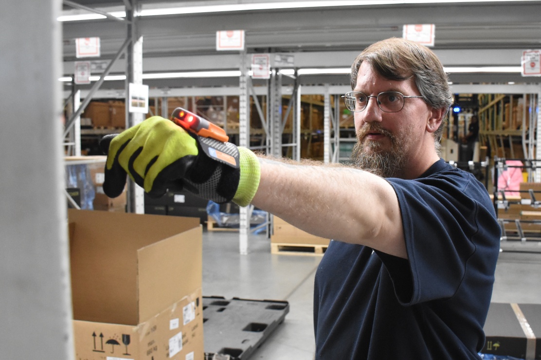 Associate demonstrates the Scanner Glove holding out his arm in logistics area. 