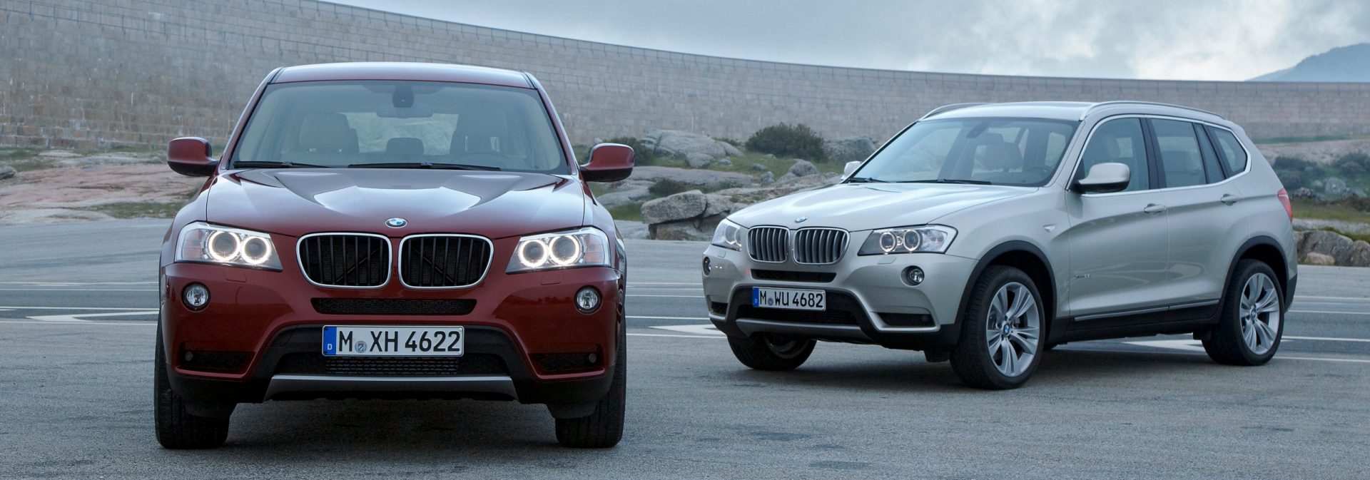 Two BMW X3 Sports Activity Vehicles parked on a road with a desert mountain background.