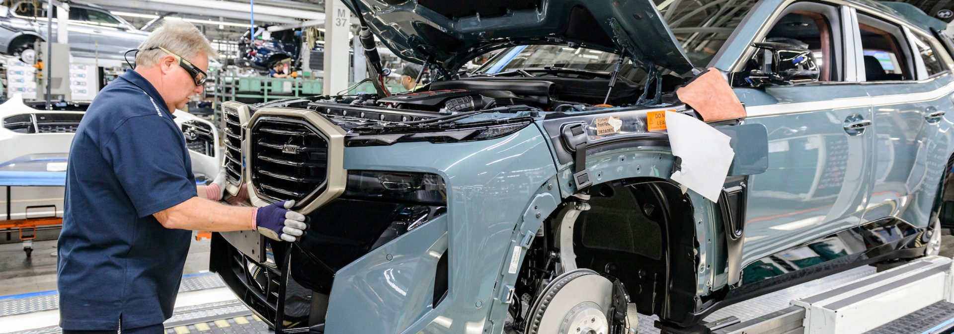 BMW XM in assembly process. Associate is installing the grille. 