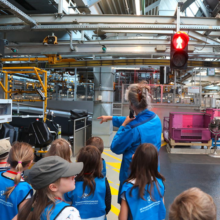 A woman shows a group of children the inside of the bmw plant