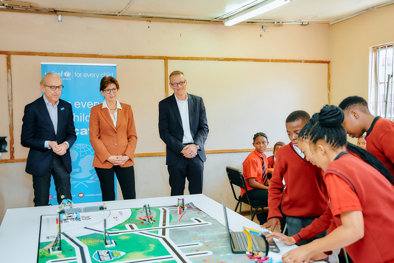 A diverse group of men and women poses together in front of a BMW stand.