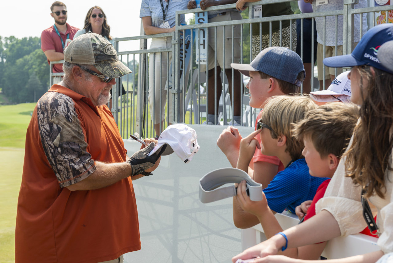 Celebrity Larry the Cable Guy signing autographs as fans line up along the golf course. 
