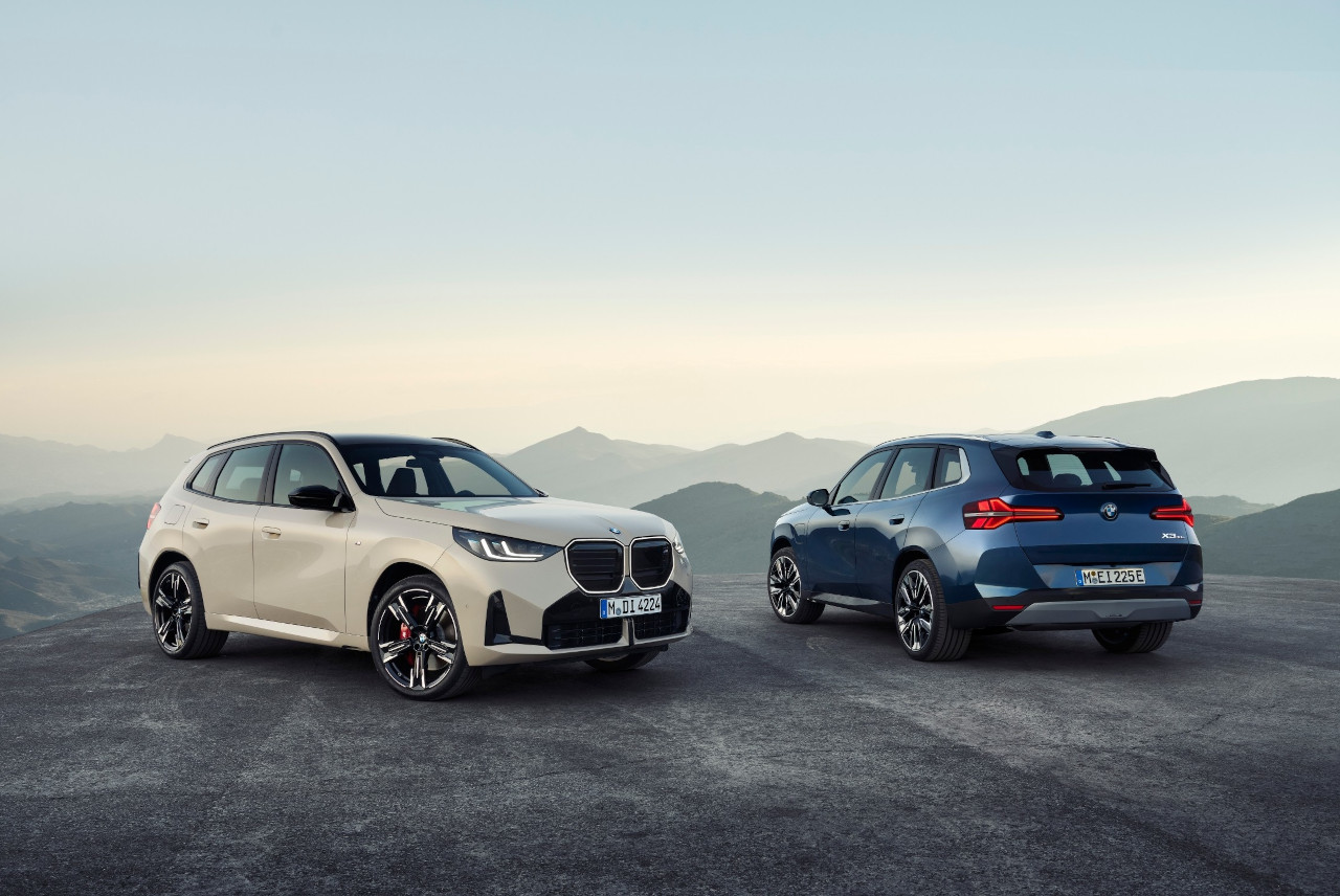 The New BMW X3 beauty shot with 2 vehicles side by side with mountains in the background.