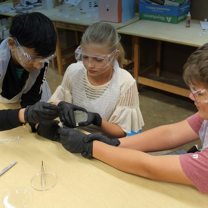 Three young students in the South Carolina Project Lead the Way program set up a lab experiment  in a class room.